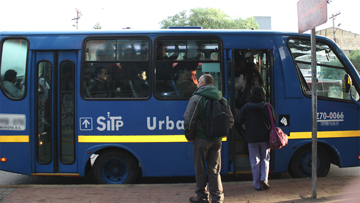 Bus Urbano estacionado en un paradero donde se esta subiendo personas